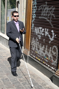 Persona ciega caminando por la calle siguiendo las indicaciones de Moovit en su teléfono